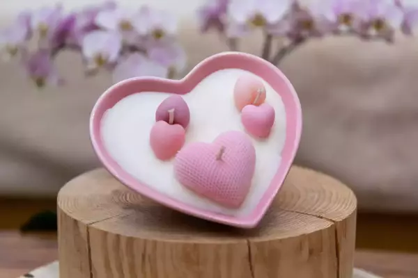 Bougie dans un pot en porcelaine en forme de cœur de couleur rose