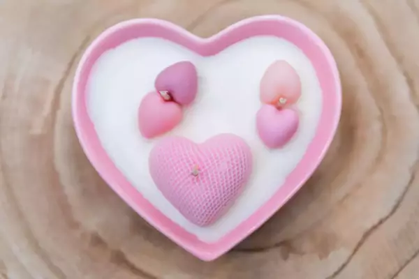 Bougie dans un pot en porcelaine en forme de cœur de couleur rose