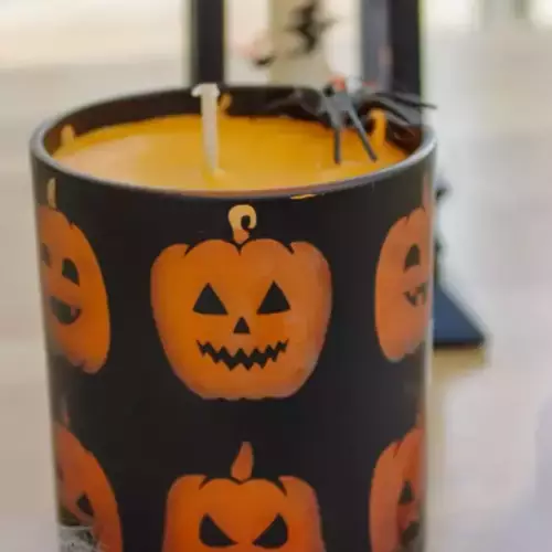 Bougie pot en verre avec citrouilles fond noir