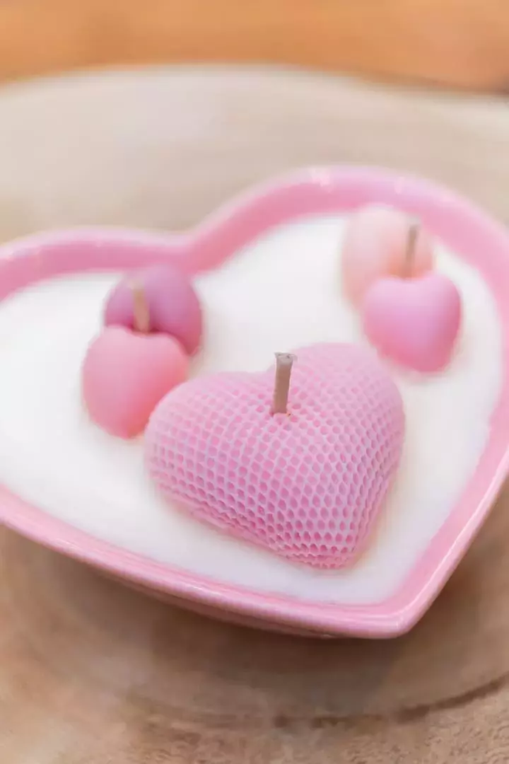 Bougie dans un contenant en porcelaine rose en forme de cœur